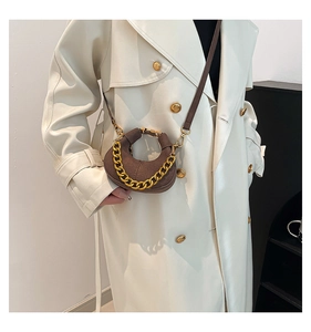Detalle del bolso de media luna marrón con cadena dorada y textura de ante elegante