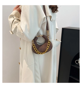 Detalle de bolso medialuna en ante marrón oscuro con cadena dorada y costuras de calidad