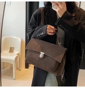 Detailed view of deep brown suede handbag featuring silver metal buckle and top handle