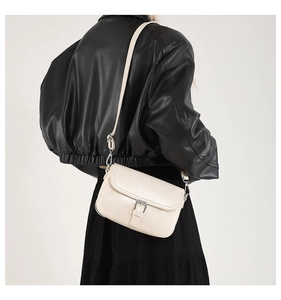 Sac à bandoulière moderne crème avec boucle en métal porté par un mannequin