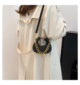 Minibandolera de media luna en cuero negro con cadena dorada sobre gabardina beige