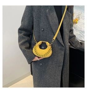 Detalle del mini bolso de media luna amarillo con cadena dorada y textura de ante