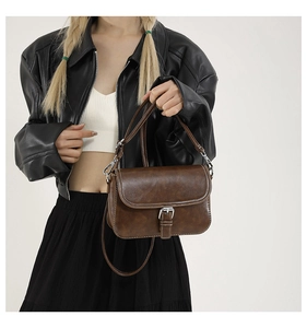 Détail d'un sac bandoulière marron vintage avec surpiqûres blanches et boucle métal