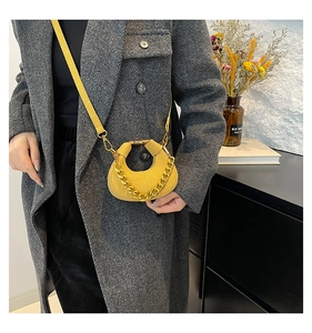Bolso media luna amarillo mostaza con cadena dorada y bandolera sobre un abrigo de lana