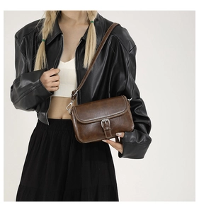 Détail du sac bandoulière vintage marron avec surpiqûres blanches et boucle en métal