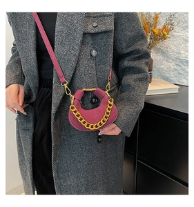 Detalle de bolso medialuna burdeos con cadena dorada en modelo con abrigo gris