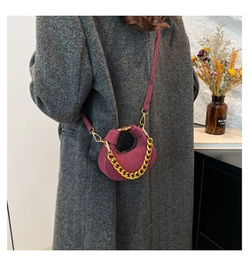 Detalle de bolso media luna granate con cadena dorada en modelo con abrigo gris
