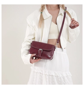 Détail du sac à rabat en cuir bordeaux avec boucle argentée et coutures contrastées