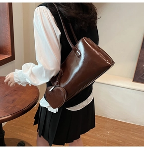 Detail of glossy dark brown tote bag with a matching heart-shaped charm accessory