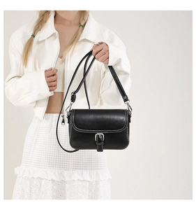 Détail du sac bandoulière noir avec surpiqûres blanches et boucle en métal argenté