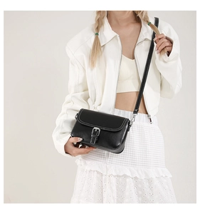 Détail du sac à bandoulière en cuir noir avec surpiqûres blanches et boucle argentée