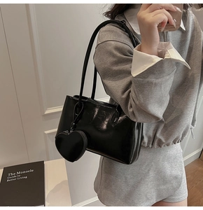 Detailed view of black glossy leather shoulder bag with a heart-shaped coin purse