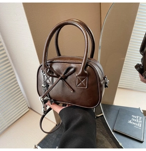 Dettaglio mini borsa bowling marrone scuro con fiocco e ciondolo a cuore argento