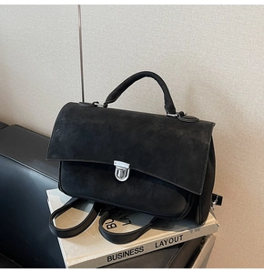 Detailed view of black matte leather briefcase featuring a silver metal twist-lock buckle