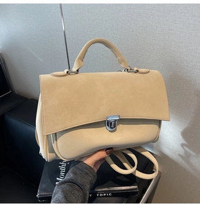 Detail view of beige matte leather messenger bag with silver metallic clasp closure