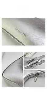 Detail of silver leather shoulder bag with metallic texture and fashion logo engraving