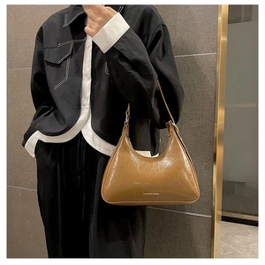 Detail of a brown glossy leather underarm bag with white printed text and silver metal buckle