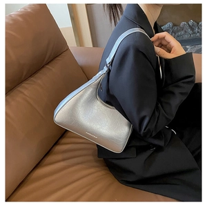 Close-up of silver metallic underarm bag with pleated texture and side zipper detail