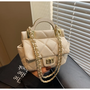 Close-up of quilted beige handbag featuring a gold semi-circular handle and turn-lock