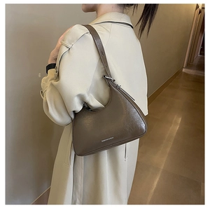 Brown moon-shaped underarm bag featuring vintage texture and adjustable strap detail