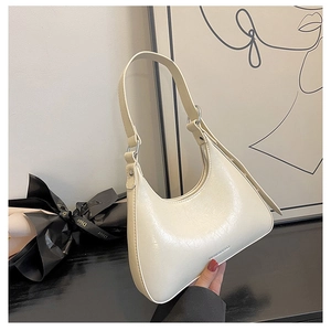 Detail of cream half-moon underarm bag with glossy pleated texture and zipper closure