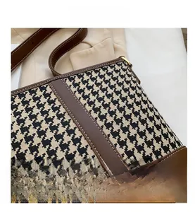 Macro view of houndstooth fabric texture with brown leather trim and golden metal buckle