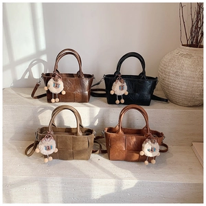 Détail de quatre sacs seaux tissés en marron, noir, vert et caramel avec breloques mouton