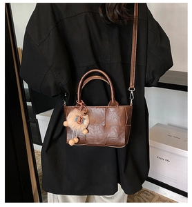 Gros plan du sac seau tissé marron avec poignées rondes et charm de lion en peluche