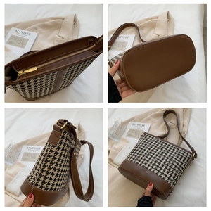 Detail view of houndstooth bucket bag featuring brown faux leather trim and gold hardware