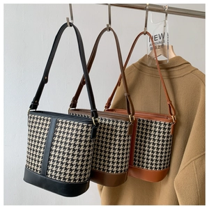 Three houndstooth bucket bags in black, brown, and camel on a metal rack