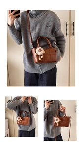 Détail du sac seau tressé marron avec charm ours en peluche amovible et bandoulière