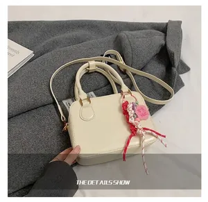 Detail show of cream white mini Boston bag with colorful woven tassel and PU leather texture