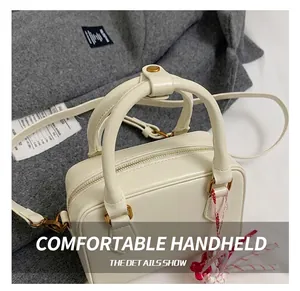 Detail of white leather Boston bag handle with matte gold metal studs and texture