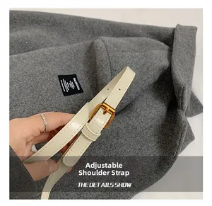 Detail of adjustable cream leather strap with gold buckle and precise stitching