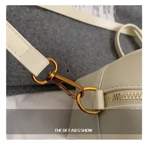 Detail view of premium golden lobster clasp and zipper on beige leather crossbody bag