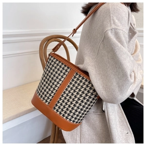 Détail d'un sac seau en pied-de-poule avec bordure en cuir marron et fine bandoulière