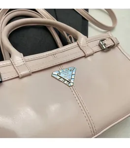 Close-up of light pink leather bag with silver triangle metal logo and fine stitching