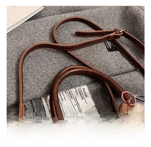 Détail du sac seau en cuir marron avec anses rondes et un joli porte-clés lion en peluche