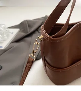 Detail shot of caramel leather bucket bag side stitching and light gold metal hardware