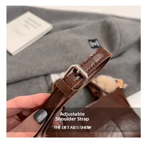 Détail du sac seau en cuir marron avec boucle réglable argentée et breloque décorative