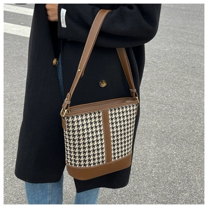 Detail of houndstooth bucket bag with brown leather trim worn by model in street style