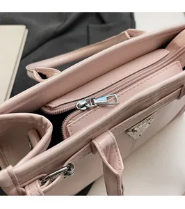 Detail of silver smooth zipper and metal logo on the minimalist pink leather handbag
