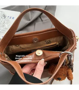 Detail of brown leather tote bag showing magnetic gold closure and branded lining