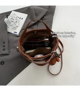 Top macro view of brown bucket bag showing large interior space and teddy pendant