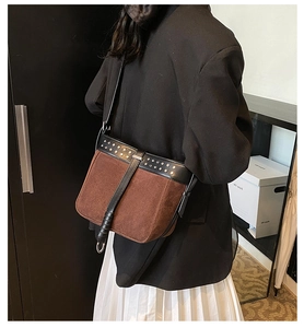 Detail of vintage brown suede crossbody bag with gold rivets and black leather trim