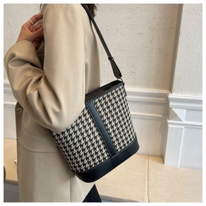 Détail du motif pied-de-poule et du cuir noir sur ce sac seau de style vintage
