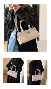 Detail view of pink leather crossbody bag with triangular metal logo and double handles
