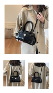 Detail view of black patent leather handbag featuring silver triangle logo and slim strap