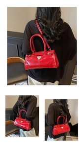 Close-up of a glossy red crossbody bag featuring a triangular metal logo and sleek finish