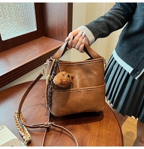 Brown PU leather bucket bag detail with adjustable strap and cute teddy bear pendant